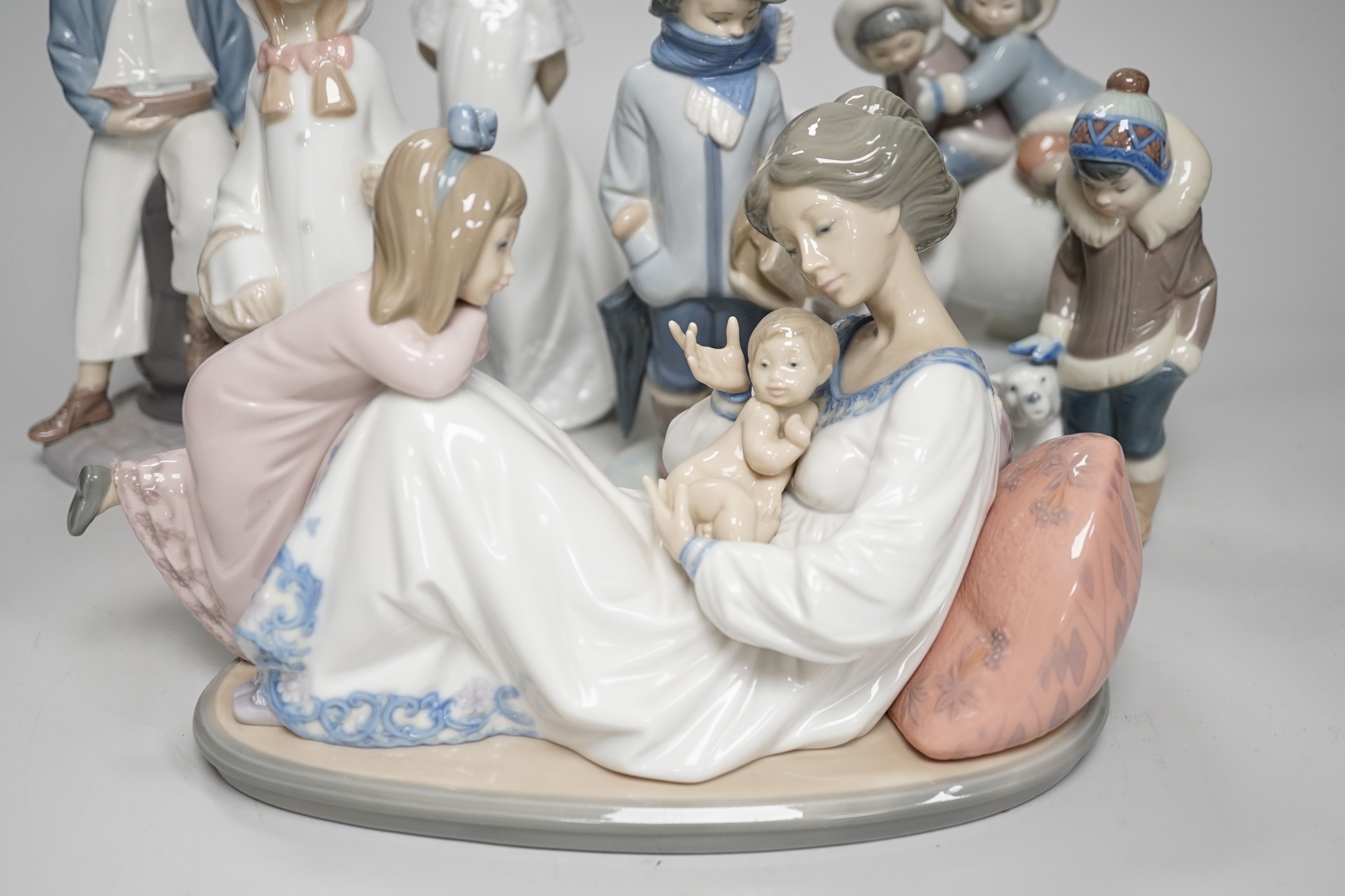 Seven Lladro figures; mother baby and child, boy with train, boy with sailing boat, Eskimo children on a polar bear and four others including a Nao example, the largest 28cm wide